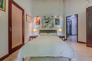 A hotel room with a large bed, two bedside tables, a nightstand, and a wall with framed artwork.