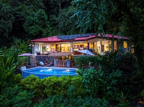 Une maison avec une piscine, entourée d’une végétation luxuriante.