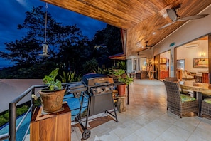An outdoor patio area with a grill, seating, and a pool.