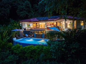 A house with a swimming pool, outdoor seating, and a bar area.
