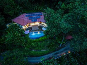 A house with a swimming pool surrounded by dense vegetation.
