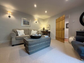 A living room with a sofa, a coffee table with a bowl, and a door leading to another room. - Redwood Cottage (Bristol)