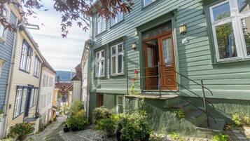 Een smalle straat met kinderafslagen met traditionele Europese gebouwen, een houten deur en een klein tuintje met bloempotten.