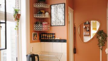 A kitchen with a kettle, shelves with spices, a framed picture, and a mirror.