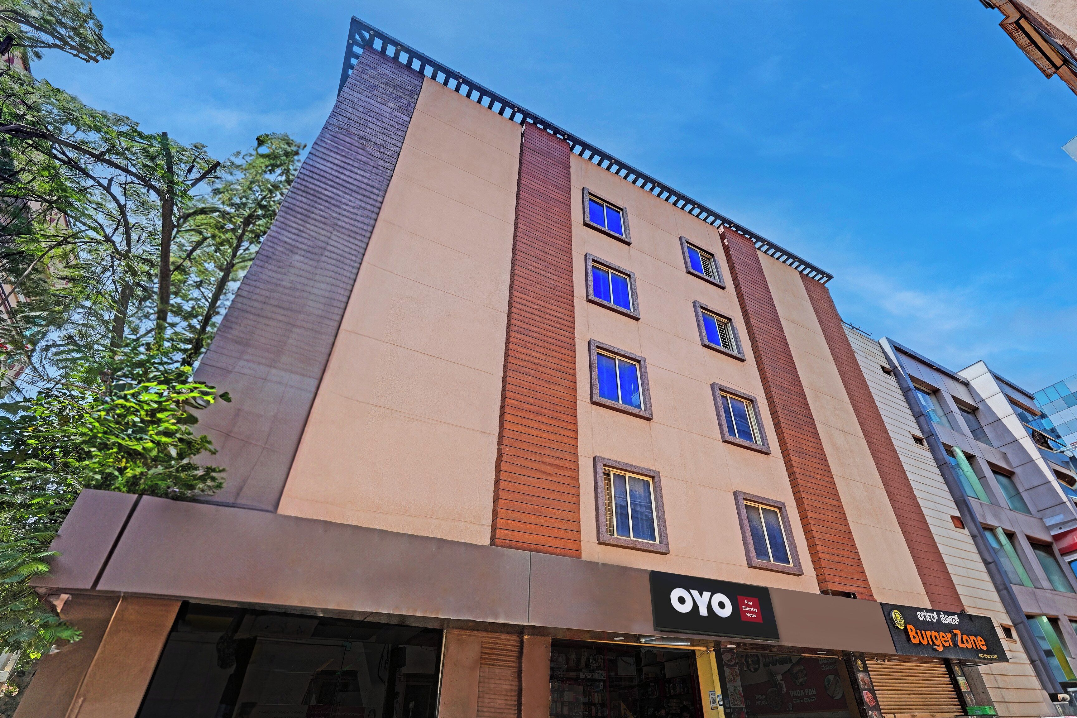 A multi-story building with a flat facade, several windows, and a storefront with a sign for 'OYO' and 'Burger Zone'.