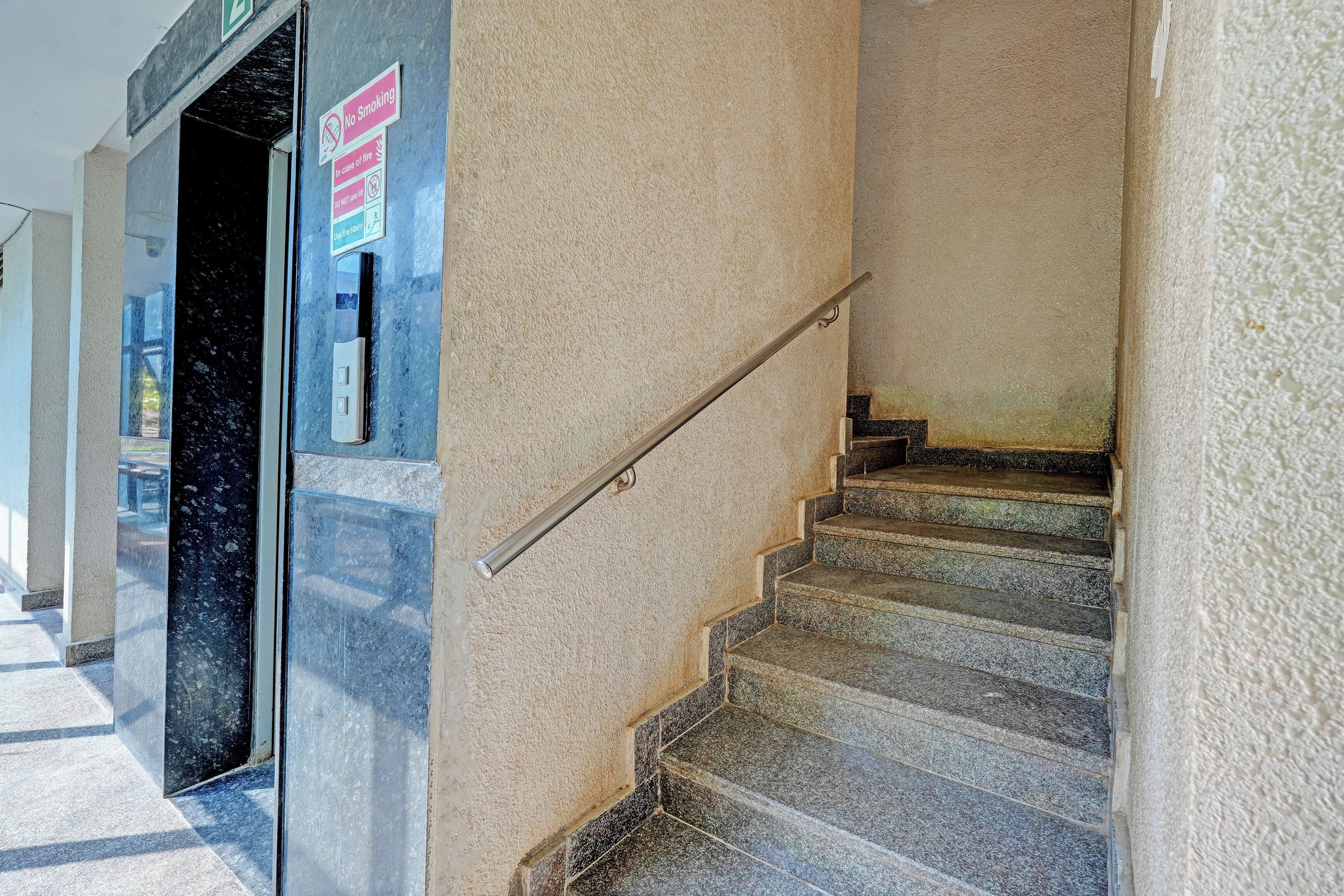 A staircase with a handrail, a 'No Smoking' sign, and a 'Use the stairs' sign.