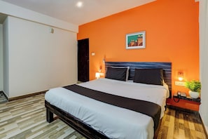 Una habitación de hotel con una cama, lámparas de noche, un teléfono, una luz en la pared y un cuadro.