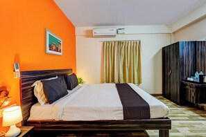 A hotel room with a bed, a bedside lamp, an air conditioning unit, a curtain, and a wardrobe. - Hotel O PMR Hotel (Bangalore)