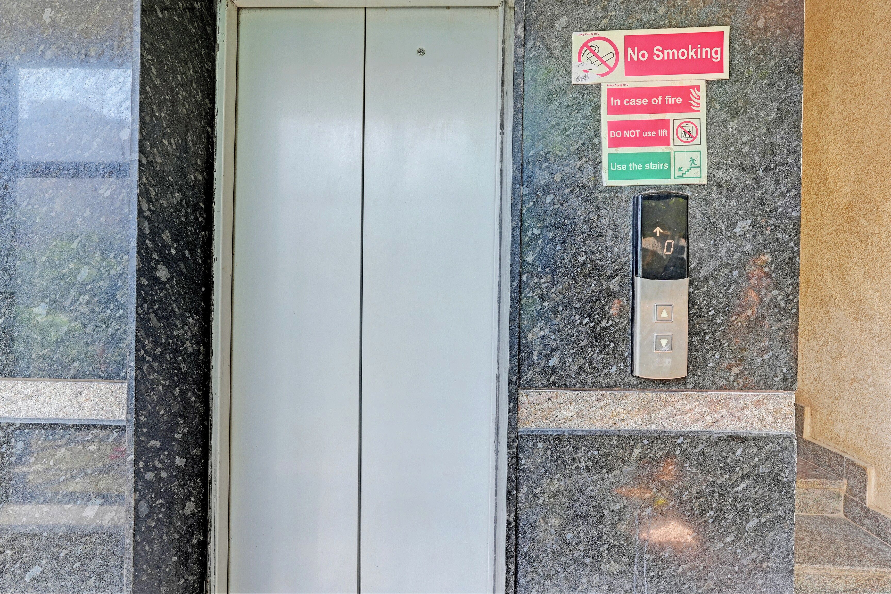 An elevator with a no-smoking sign, a fire safety sign, and a lift control panel.