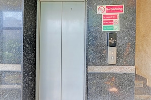 Un ascensor con un cartel de prohibido fumar, un rótulo de seguridad contra incendios y un panel de control.