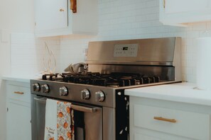 A kitchen with a stainless steel stove, white cabinets, and a tiled backsplash. - Cozy Retreat Near Downtown Seguin & New Braunfels (Seguin)