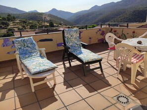 A terrace with two lounge chairs and a table, overlooking a mountainous landscape. - SIERRA DE FRANCIA APARTMENTS IN THE HEART OF THE LAS BATUECAS RESERVE AND NATURAL PARK (Monsagro)