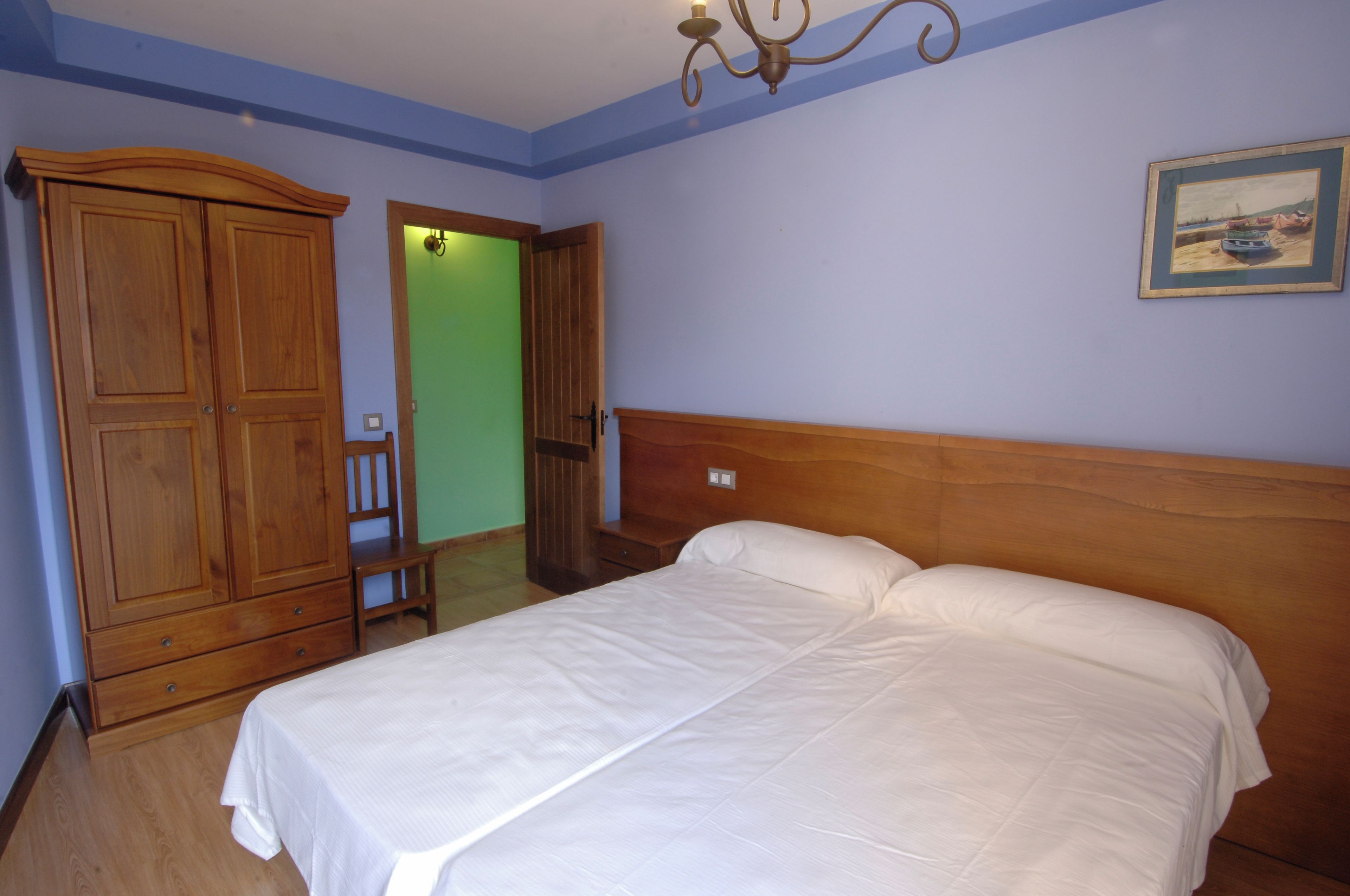 A bedroom with a wooden bed, a wardrobe, and a door leading to another room.