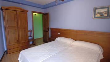 A bedroom with a wooden bed, a wardrobe, and a door leading to another room.
