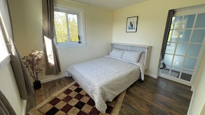 A bedroom with a bed, a window, a door, and a checkered rug. - Modern 5-Acre Barn Loft • Mt. Rainier & Crystal Mountain Basecamp • Pet Friendly (Enumclaw)