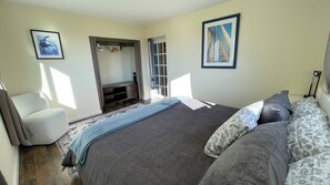 A bedroom with a bed, a chair, a wardrobe, and a door leading to another room.