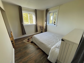 A bedroom with a bed, a window, a chair, and a wooden floor. - Modern 5-Acre Barn Loft • Mt. Rainier & Crystal Mountain Basecamp • Pet Friendly (Enumclaw)
