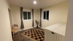 A room with two windows, a chair, a checkered rug, and a radiator. - Modern 5-Acre Barn Loft • Mt. Rainier & Crystal Mountain Basecamp • Pet Friendly (Enumclaw)