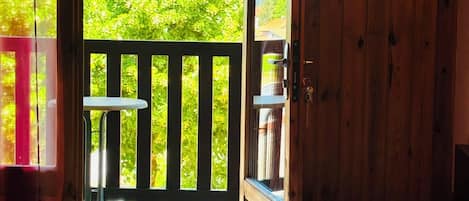 A bedroom with a bed, a wooden door leading to an outdoor balcony, and a small table.