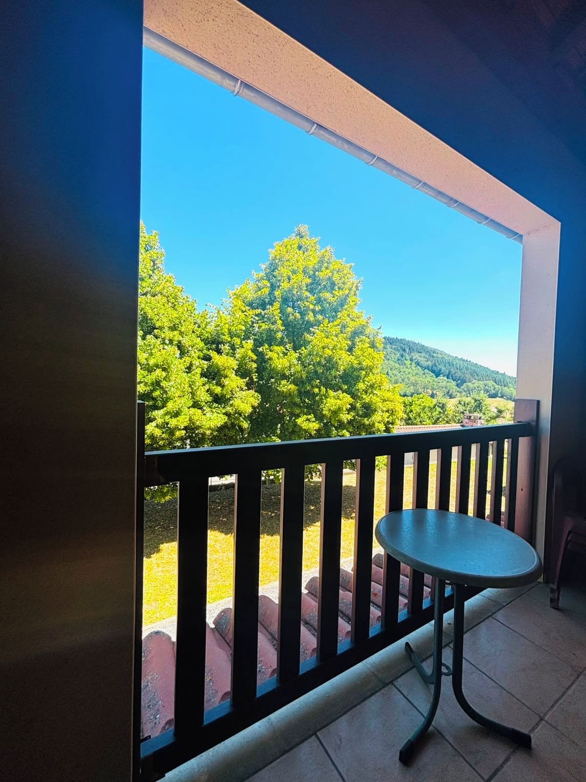 Un balcon donnant sur un paysage verdoyant, avec une table.