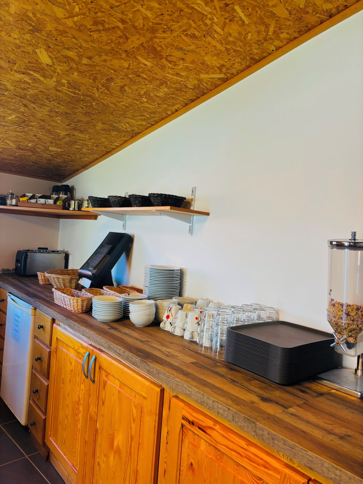 A kitchen with wooden cabinets, a toaster, a coffee maker, and a food dispenser.