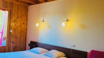 Habitación de cabaña de madera con una cama, dos luces fijadas a la pared y una lámpara colgante.