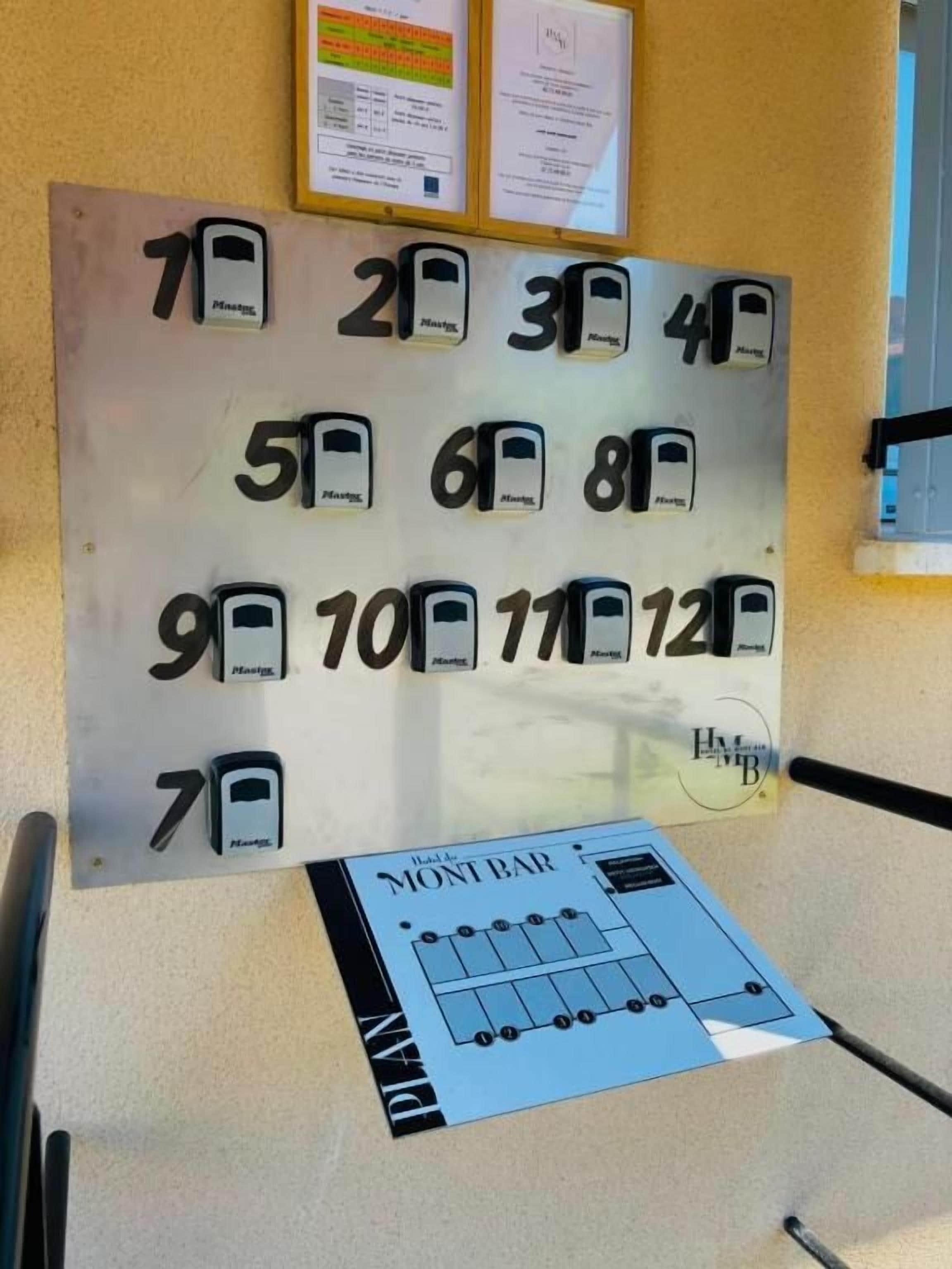 Una pared con placas de habitaciones numeradas y un plano de planta sobre una mesa.