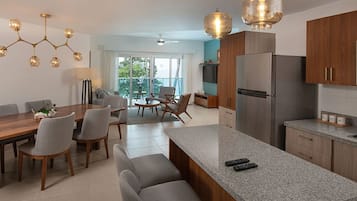 Une cuisine moderne dotée d’un îlot central, d’un coin repas avec une table et des chaises, et offrant une vue sur l’extérieur grâce à de grandes fenêtres.