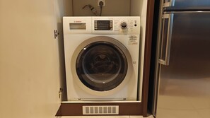 Eine kompakte Bosch Waschmaschine mit Bedienfeld und Steckdose darüber.