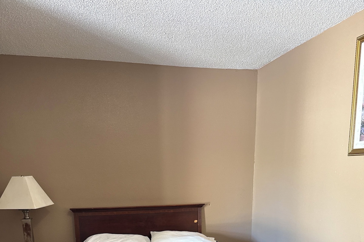 A bedroom with a bed, a nightstand, and a lamp.