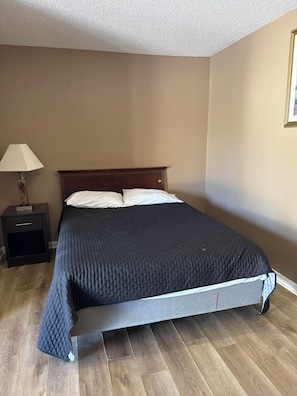 A bedroom with a bed, a nightstand, and a lamp. - Sparta Motel 7 (Sparta)