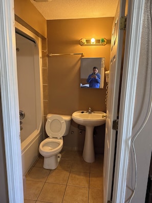 A bathroom with a toilet, sink, and a mirror. - Sparta Motel 7 (Sparta)