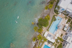 An aerial view of a coastal hotel with a swimming pool, palm trees, and beach access. - Imperial Suites Cabarete- 3 bedrooms (Cabarete)