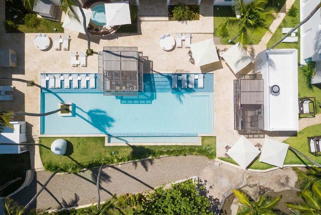 A rooftop swimming pool with sun loungers, a covered seating area, and a gated entrance.