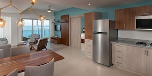A modern kitchen with a stainless steel refrigerator, wooden cabinets, and a dining area with a table and chairs. - Imperial Suites Cabarete- 3 bedrooms (Cabarete)