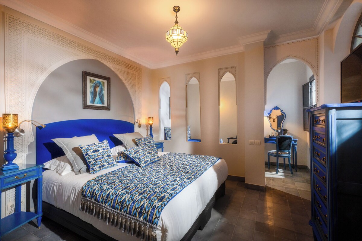 Habitació d'hotel amb un llit gran, una taula de nit i un armari.