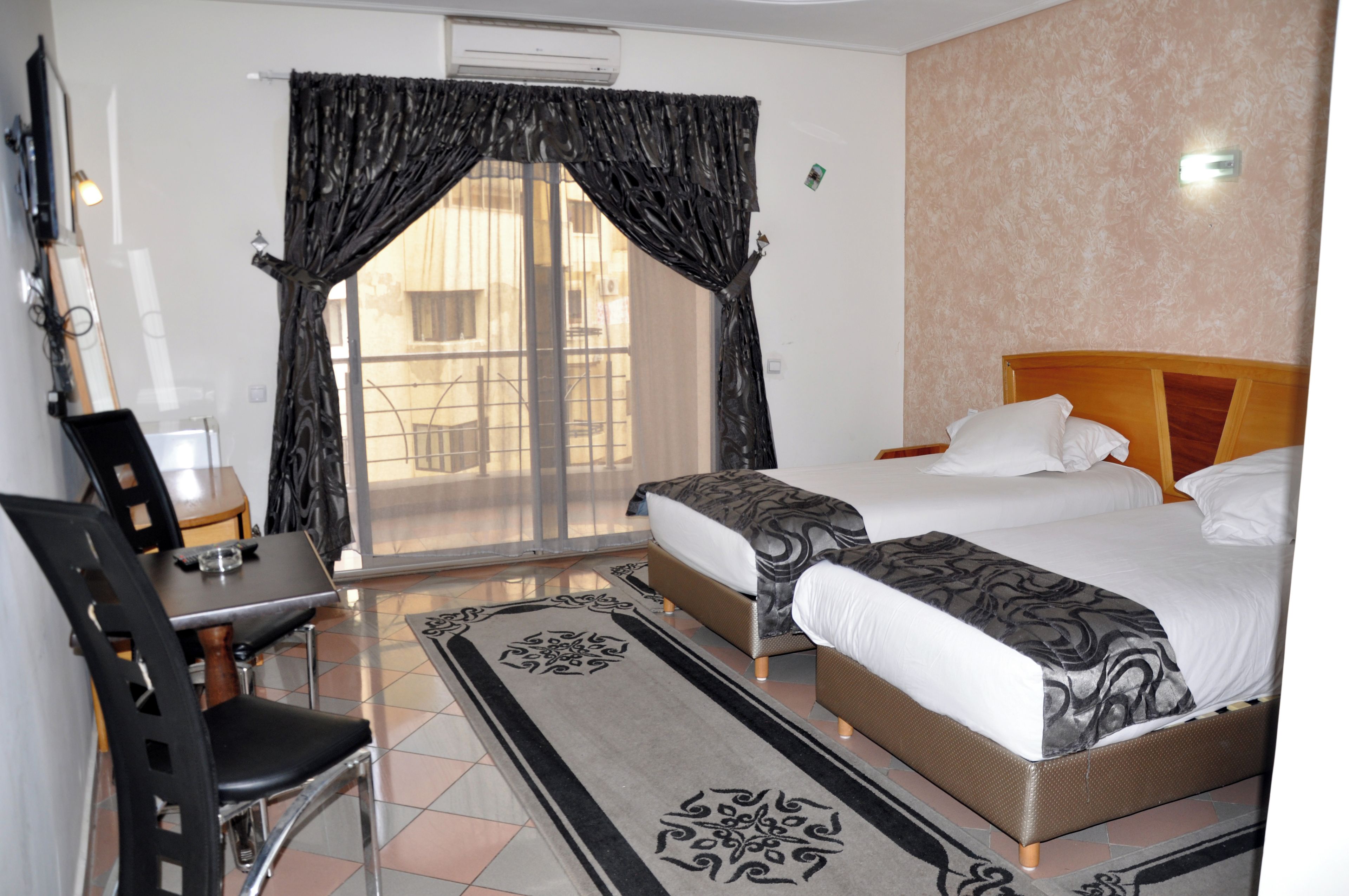 A hotel room with a bed, two bedside tables, a chair, a desk, and a window with curtains.