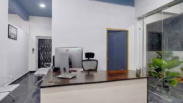 A reception desk with a computer, chair, and a door in a modern office space.
