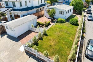 A residential area with a white house, a fenced yard, and a parked car. - Charming 2-bedroom house in centrally located Mill Valley neighborhood (Mill Valley)