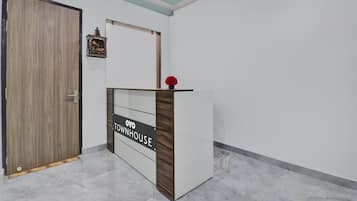A reception desk with a sign reading 'OYO TOWNHOUSE' in a modern interior with a wooden door and a ceiling light.