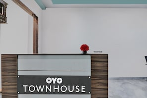 A reception desk with a sign that reads 'OYO TOWNHOUSE' and a 'RECEPTION' label above it. - Collection O Hotel Blueline (Kanpur)