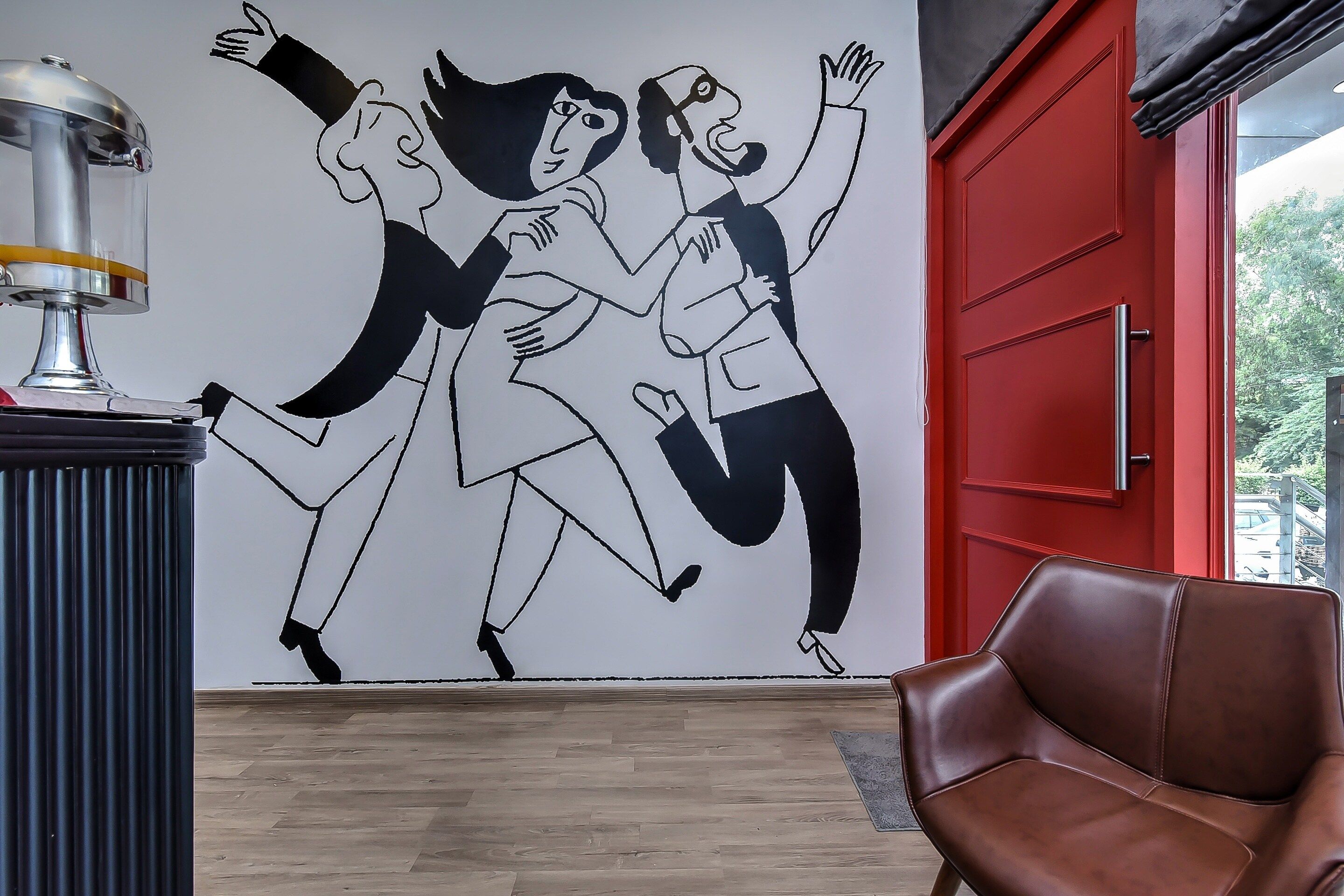 A room with a red door, a brown leather chair, and a wall mural.