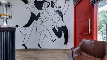 A room with a red door, a brown leather chair, and a wall mural.