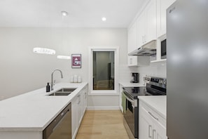A modern kitchen with white cabinetry, a stainless steel refrigerator, and a built-in oven.