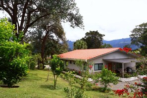 A house with a red tiled roof, surrounded by lush greenery and a mountainous backdrop. - VILLA ALESSANDRA – TU ESCAPADA PERFECTA EN BAJO BOQUETE (bajo Boquete)