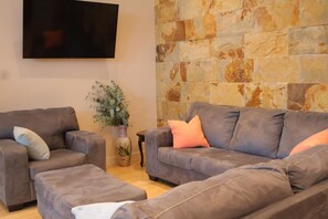 Ein Wohnzimmer mit zwei Sofas, einem Couchtisch und einem an der Wand befestigten Flachbildfernseher.