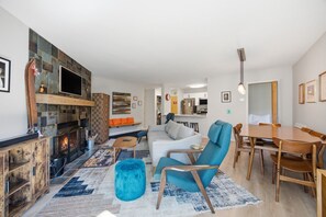 A modern living room with a fireplace, seating area, and a dining space. - Family friendly 3br Condo on Okemo Shuttle Route just minutes from Okemo (Ludlow)
