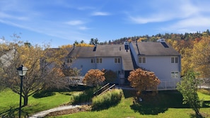 A two-story house with a sloped roof, a front porch, and a small bridge leading to the entrance. - Family friendly 3br Condo on Okemo Shuttle Route just minutes from Okemo (Ludlow)