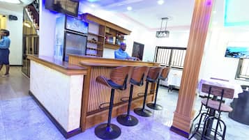 Un espace bar avec un comptoir en bois, des tabourets de bar et un réfrigérateur.
