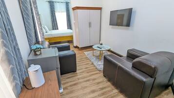 Una habitación de hotel moderna con una cama, un sofá, una mesita, un televisor y un armario.